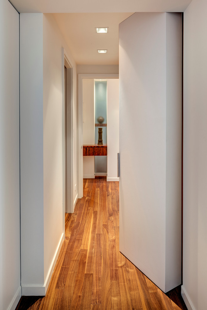 На фото: коридор среднего размера в современном стиле с белыми стенами и темным паркетным полом с