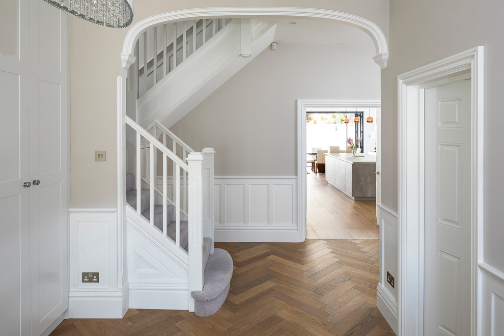 Esempio di un ingresso o corridoio classico di medie dimensioni con pavimento in legno massello medio, pavimento marrone, pareti beige e pannellatura