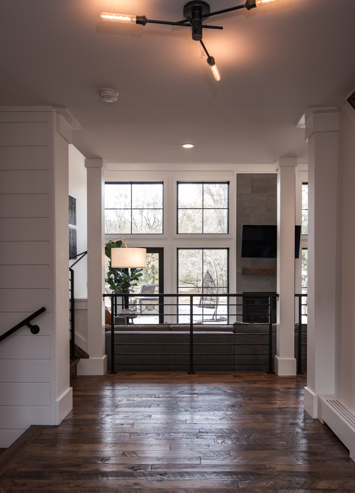 Idée de décoration pour un grand couloir minimaliste avec un mur blanc, parquet foncé et un sol marron.