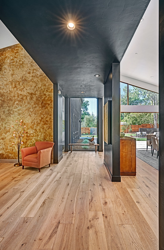 Idées déco pour un couloir contemporain de taille moyenne avec un mur noir, un sol en bois brun et un sol marron.