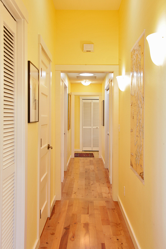 Inspiration for a mid-sized timeless light wood floor hallway remodel in Seattle with yellow walls