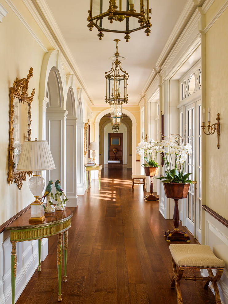 Foto de recibidores y pasillos clásicos con paredes amarillas, suelo de madera en tonos medios y suelo marrón