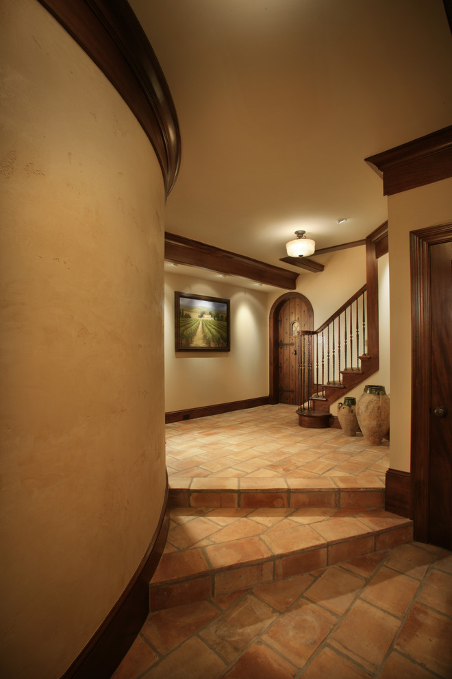 Ejemplo de recibidores y pasillos tradicionales con paredes beige, suelo rojo y iluminación