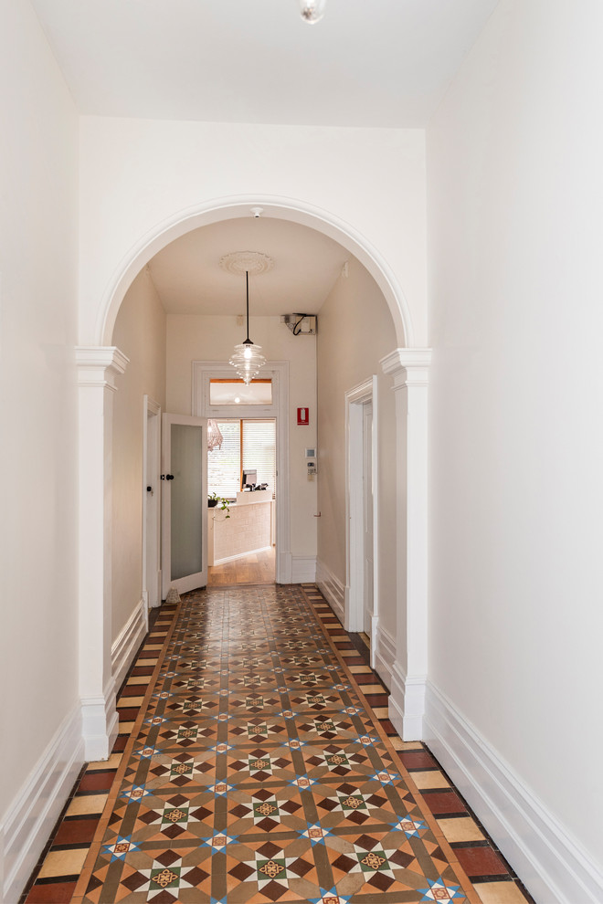 На фото: большой коридор в классическом стиле с белыми стенами, полом из керамической плитки и разноцветным полом