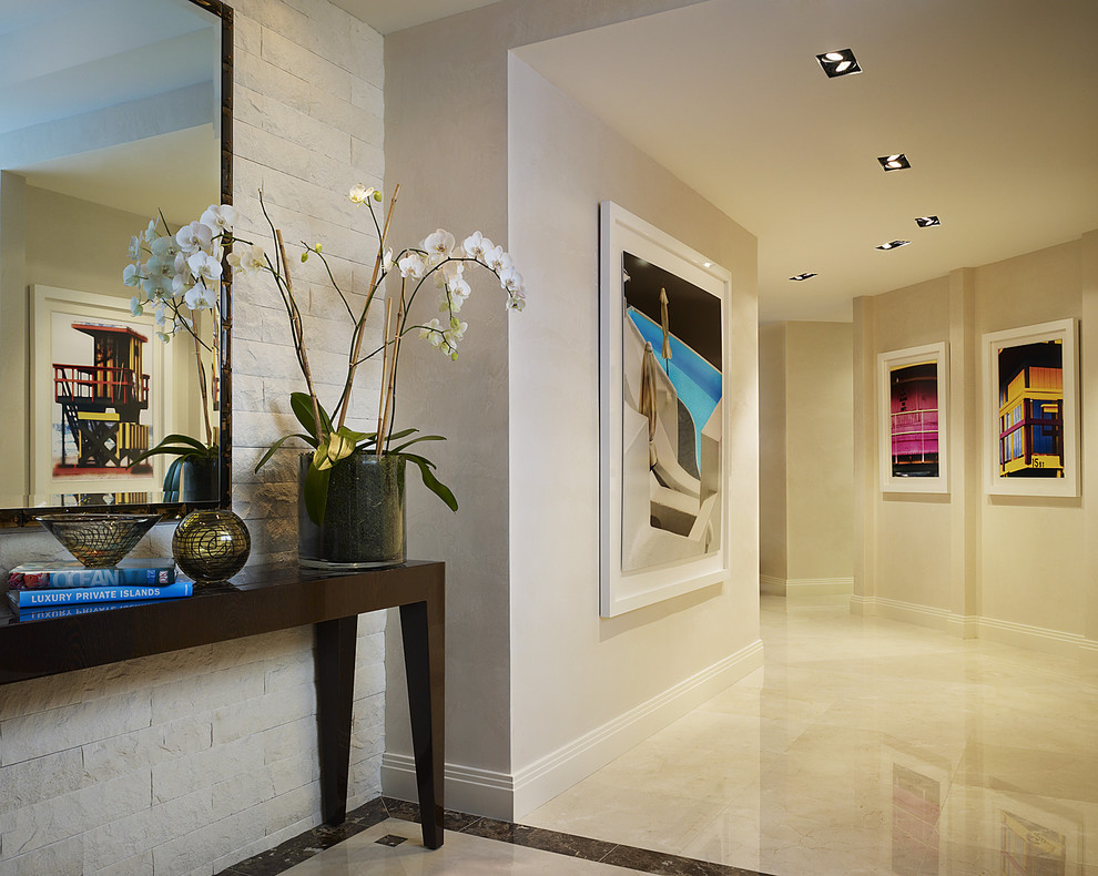 Idée de décoration pour un grand couloir design avec un sol en marbre, un mur beige et un sol blanc.