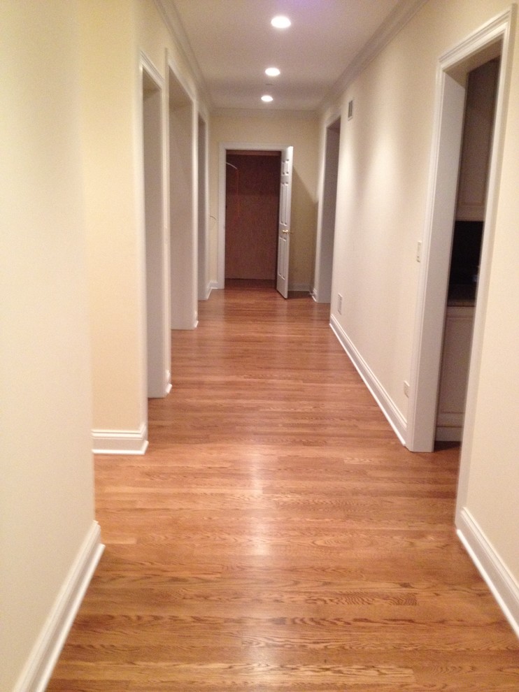 Cette image montre un couloir traditionnel de taille moyenne avec un mur beige, un sol en bois brun et un sol marron.
