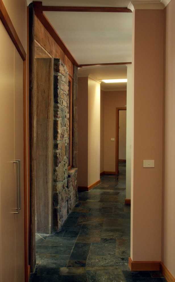 На фото: коридор среднего размера в стиле рустика с полом из сланца и коричневыми стенами с