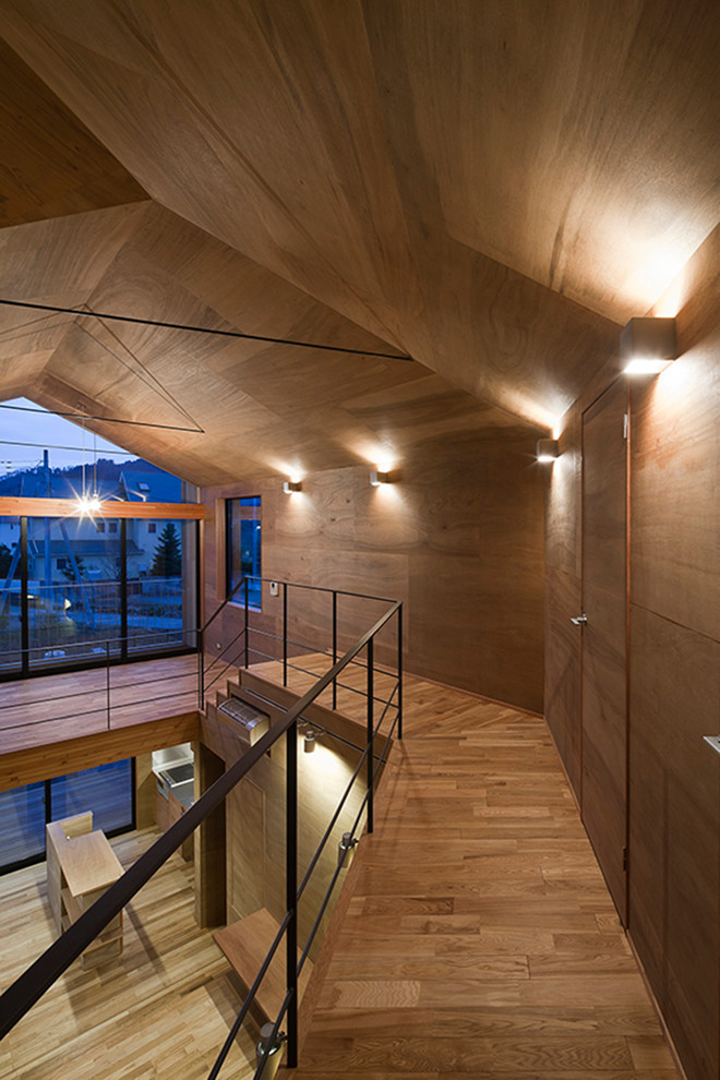 Réalisation d'un couloir design avec un mur marron et un sol en bois brun.