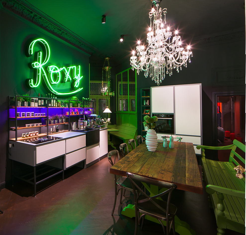 This is an example of a large eclectic single-wall breakfast bar in Berlin with a built-in sink, flat-panel cabinets, white cabinets, black splashback, brown floors and white worktops.