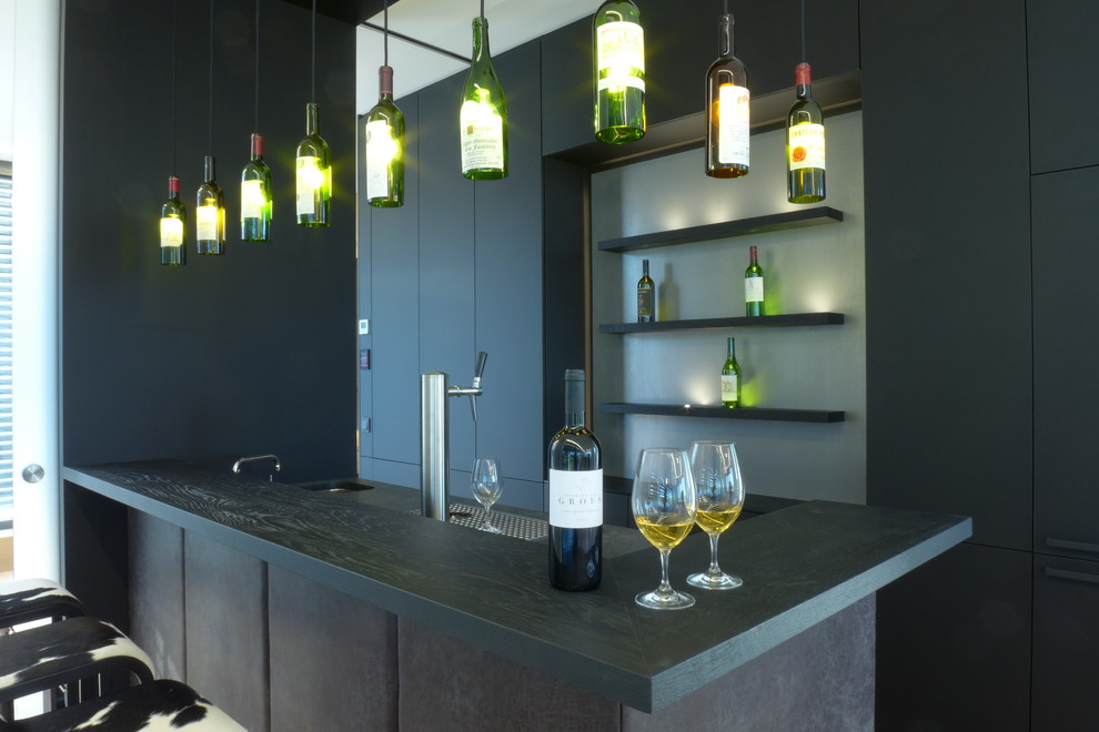 This is an example of a large contemporary l-shaped wet bar in Frankfurt with a submerged sink, black cabinets, wood worktops, black splashback, black worktops and flat-panel cabinets.