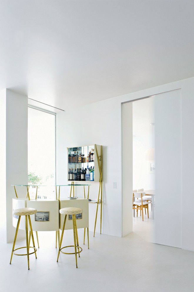 Einzeilige, Geräumige Moderne Hausbar mit Bartheke, weißen Schränken, Glas-Arbeitsplatte, Rückwand aus Spiegelfliesen, Betonboden und grauem Boden in München