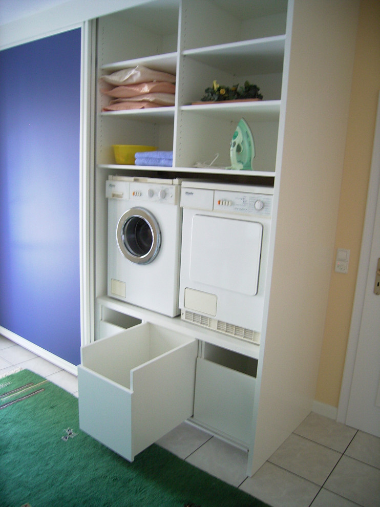 他の地域にある高級な広いコンテンポラリースタイルのおしゃれな家事室 (I型、フラットパネル扉のキャビネット、青いキャビネット、目隠し付き洗濯機・乾燥機) の写真