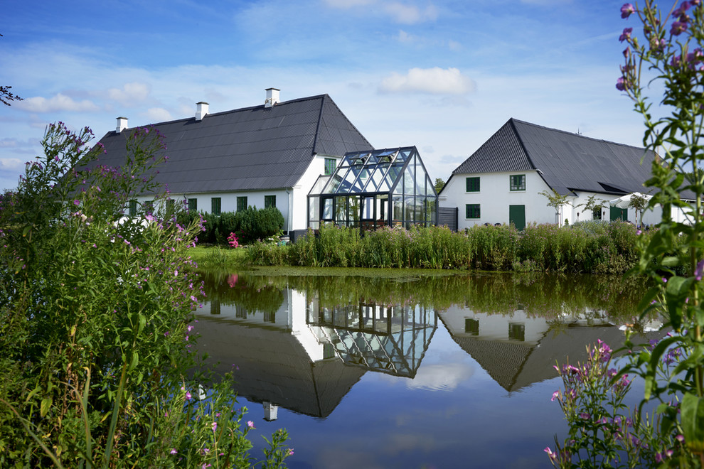 This is an example of a large farmhouse side full sun garden in Odense with a pond.