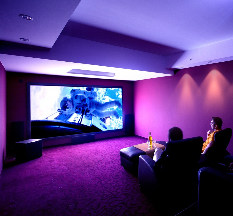 Réalisation d'une salle de cinéma design de taille moyenne et fermée avec un mur rouge, moquette et un écran de projection.