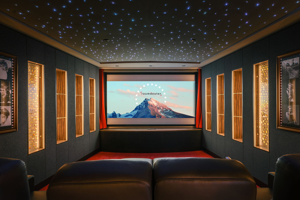 Réalisation d'une grande salle de cinéma design avec un mur gris, moquette, un écran de projection et un sol rouge.