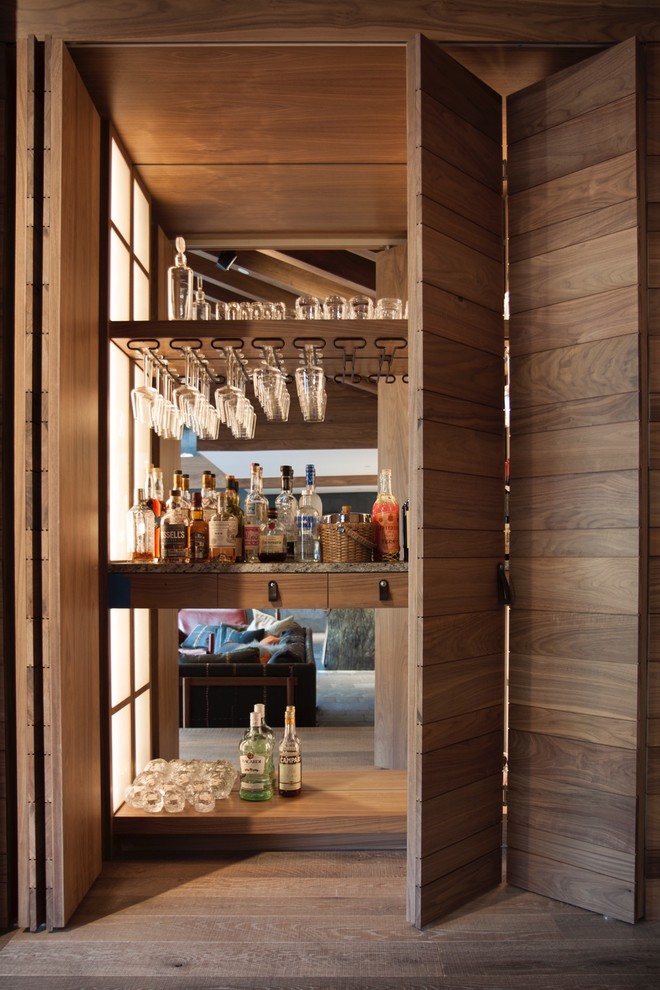 Foto de bar en casa moderno extra grande sin pila con puertas de armario de madera oscura, encimera de mármol, salpicadero con efecto espejo y suelo de madera en tonos medios