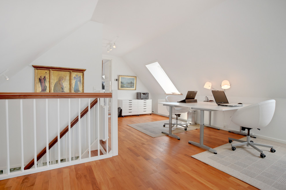 Réalisation d'un bureau nordique avec un mur blanc, un sol en bois brun et un bureau indépendant.