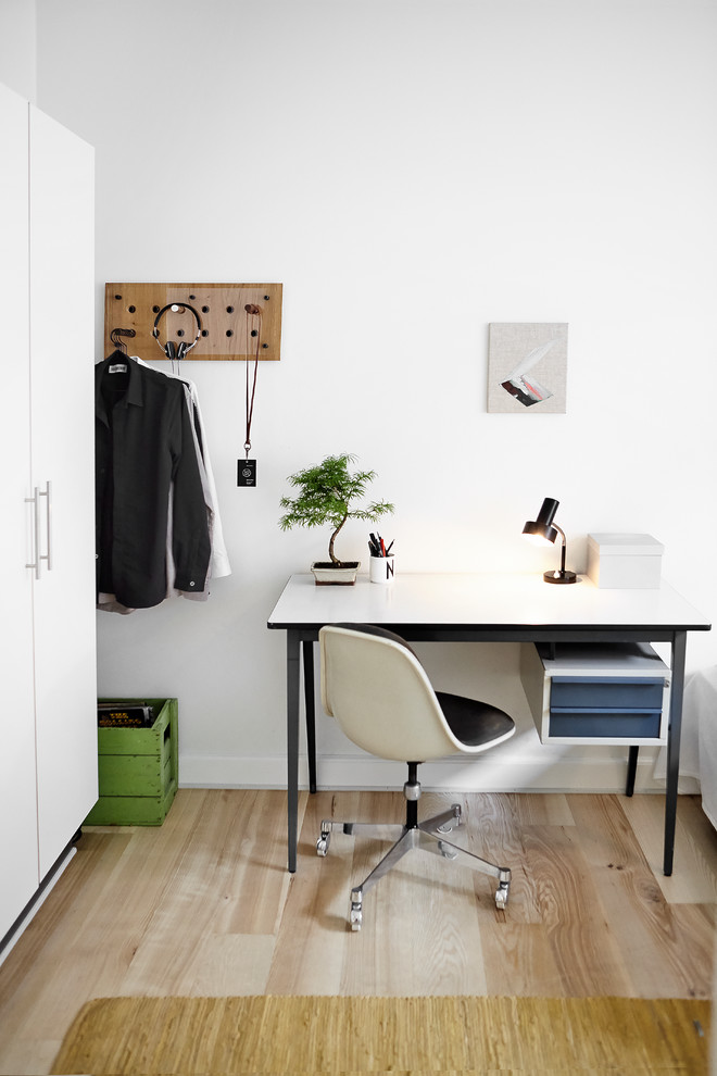 Foto de despacho nórdico con paredes blancas, suelo de madera clara y escritorio independiente