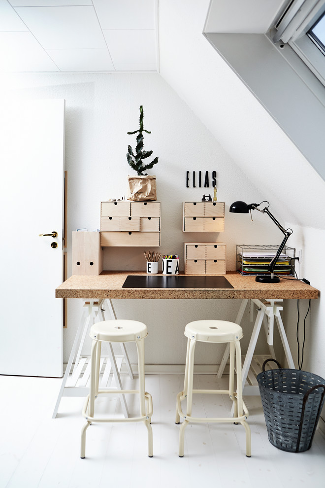 На фото: кабинет в скандинавском стиле с белыми стенами, деревянным полом и отдельно стоящим рабочим столом с