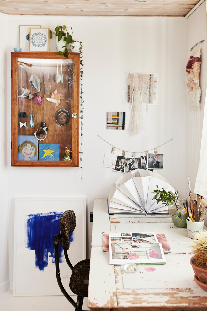Bild på ett eklektiskt hobbyrum, med vita väggar och ett fristående skrivbord