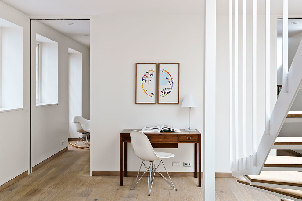 Small scandi home office in Copenhagen with white walls, a freestanding desk and beige floors.
