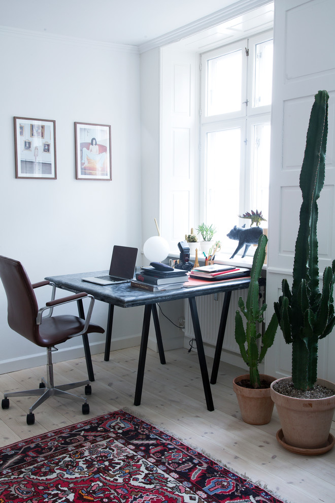 Diseño de despacho escandinavo grande sin chimenea con paredes blancas, suelo de madera clara y escritorio independiente