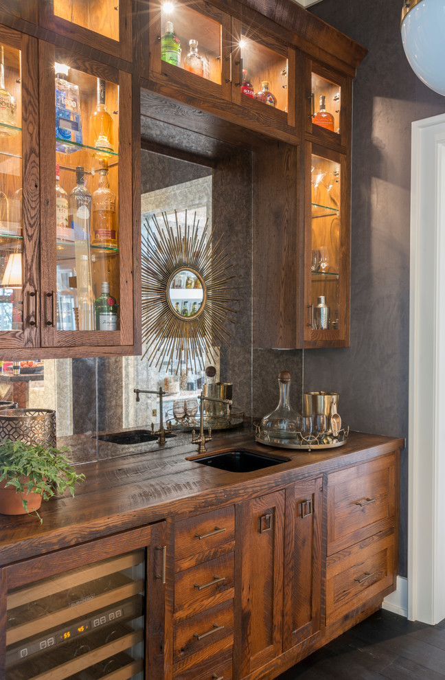 Wet bar - large transitional single-wall dark wood floor wet bar idea in Charleston with an undermount sink, glass-front cabinets, medium tone wood cabinets, wood countertops, mirror backsplash and brown countertops