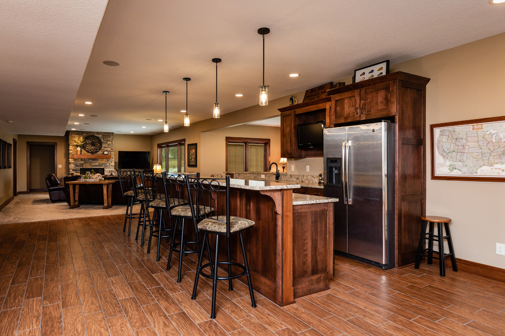 Example of a large arts and crafts single-wall medium tone wood floor and brown floor wet bar design in Other with an undermount sink, shaker cabinets, dark wood cabinets, granite countertops and multicolored countertops