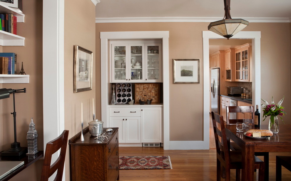 Amerikansk inredning av en liten beige linjär beige hemmabar med vask, med skåp i shakerstil, vita skåp, mellanmörkt trägolv och brunt golv