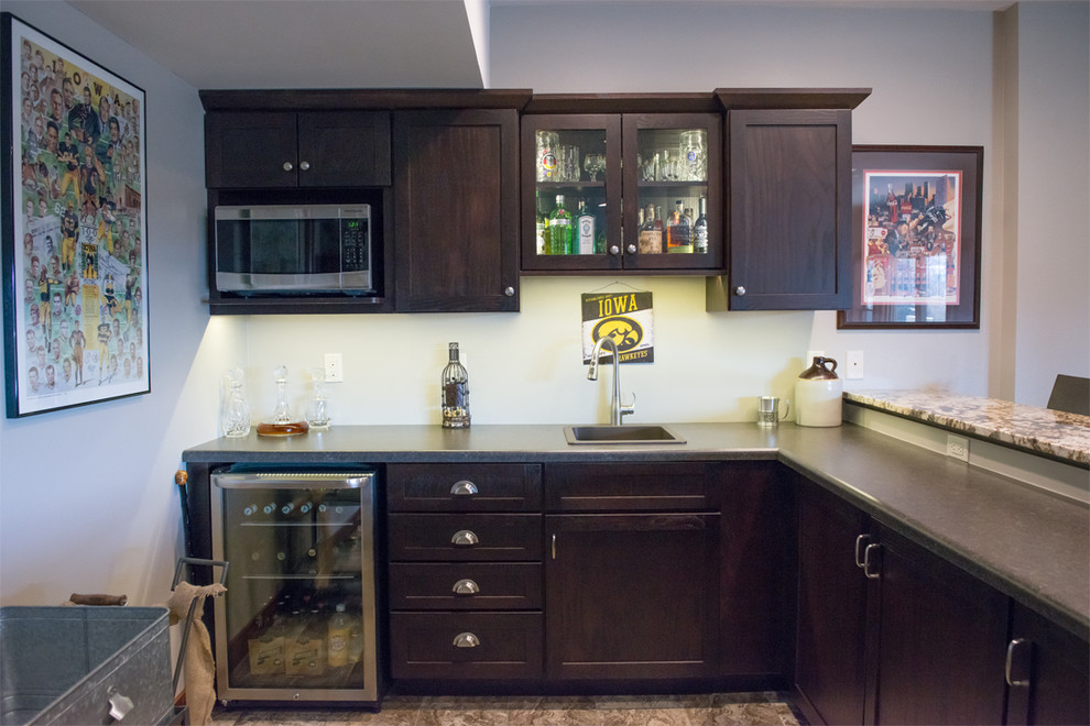 Large arts and crafts l-shaped travertine floor seated home bar photo in Cedar Rapids with shaker cabinets, dark wood cabinets, laminate countertops and a drop-in sink