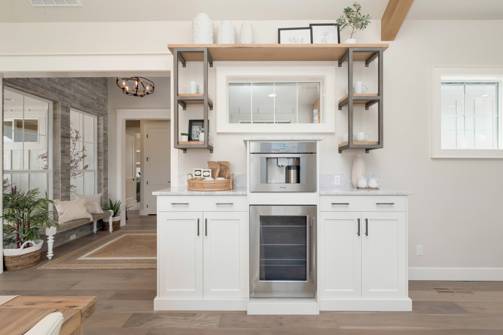 Inspiration for a medium sized rural single-wall home bar in Boise with recessed-panel cabinets, white cabinets, marble worktops, light hardwood flooring, beige floors and grey worktops.