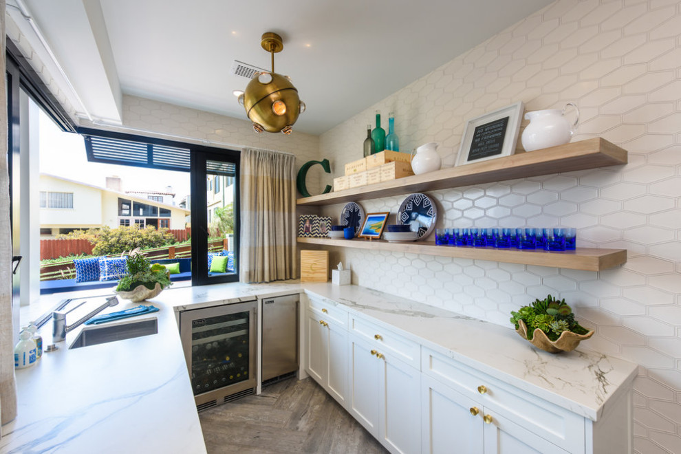 Mid-sized beach style u-shaped porcelain tile and beige floor wet bar photo in Los Angeles with an undermount sink, shaker cabinets, white cabinets, quartz countertops, white backsplash, ceramic backsplash and white countertops