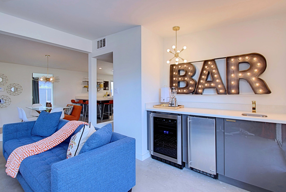 Inspiration for a mid-sized mid-century modern single-wall concrete floor wet bar remodel in Phoenix with an undermount sink, flat-panel cabinets, gray cabinets, quartz countertops and white backsplash