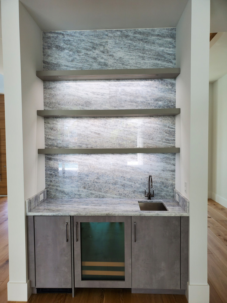 Bild på en liten funkis flerfärgade linjär flerfärgat hemmabar med vask, med en undermonterad diskho, släta luckor, grå skåp, bänkskiva i kvarts, flerfärgad stänkskydd och ljust trägolv