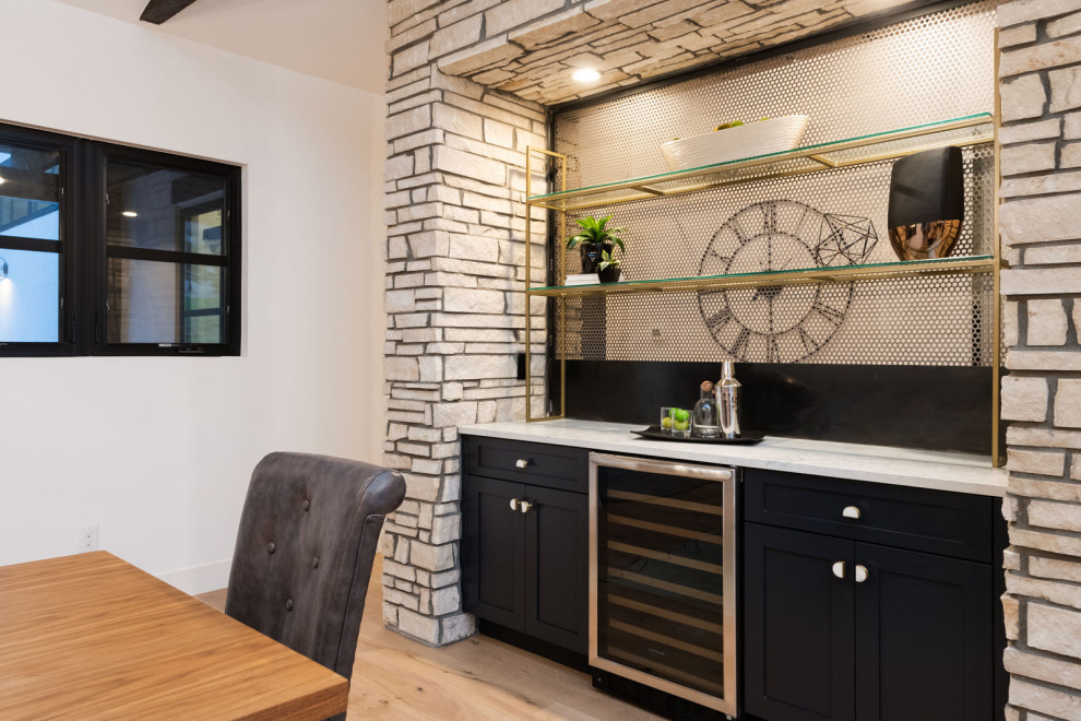 Diseño de bar en casa minimalista con armarios estilo shaker, puertas de armario negras, encimera de cuarcita, suelo de madera clara y encimeras blancas