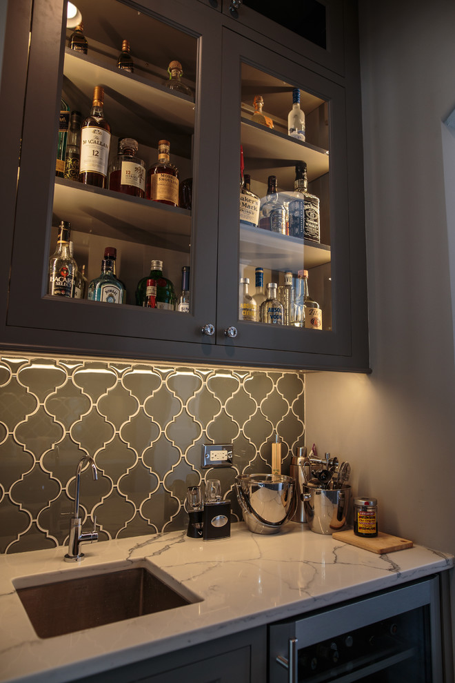 Large traditional single-wall wet bar in Chicago with a submerged sink, shaker cabinets, marble worktops, glass tiled splashback, dark hardwood flooring, grey cabinets and grey splashback.