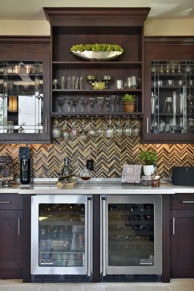 Cette photo montre un grand bar de salon chic en bois foncé avec un placard à porte shaker, un plan de travail en surface solide, un sol en travertin, une crédence marron et une crédence en carreau briquette.