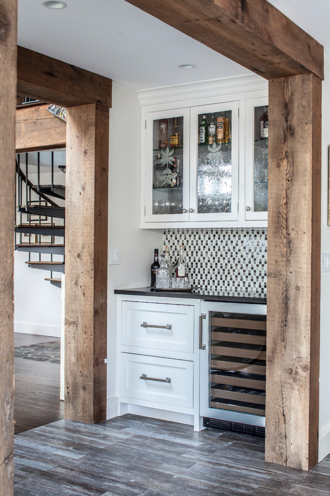 Photo of a rural wet bar in New York with recessed-panel cabinets, white cabinets, wood worktops, glass tiled splashback and porcelain flooring.