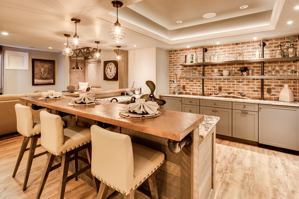 Geräumige Urige Hausbar in L-Form mit Bartheke, beigen Schränken, Granit-Arbeitsplatte und hellem Holzboden in Baltimore