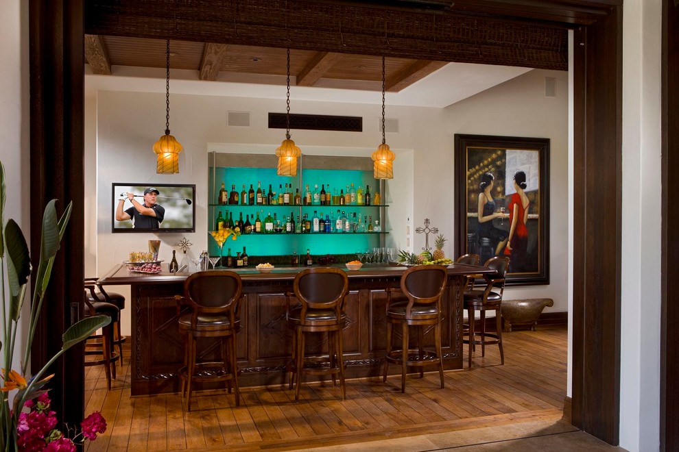 Пример оригинального дизайна: п-образный домашний бар в средиземноморском стиле с паркетным полом среднего тона, барной стойкой, темными деревянными фасадами, деревянной столешницей, синим фартуком, коричневым полом и коричневой столешницей