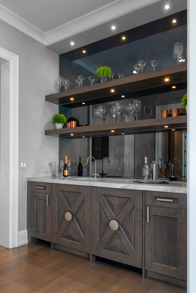 Inspiration for a large country wet bar in Detroit with distressed cabinets, marble worktops, mirror splashback, medium hardwood flooring and brown floors.