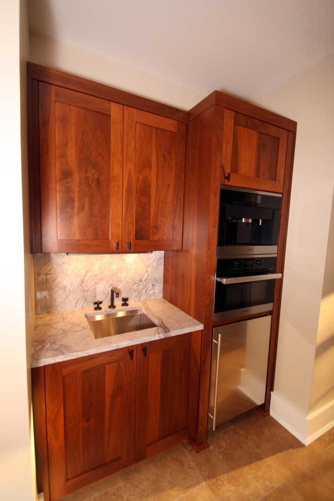 Photo of a small traditional single-wall home bar in Indianapolis with a submerged sink, medium wood cabinets, marble worktops, grey splashback, stone slab splashback, ceramic flooring, shaker cabinets and beige floors.