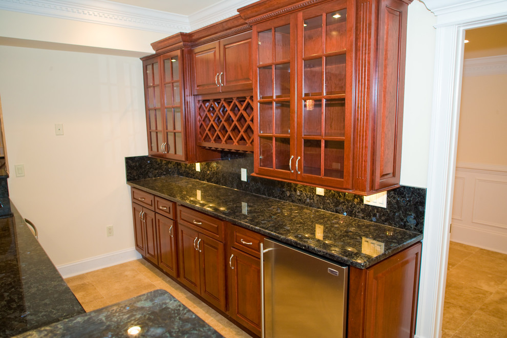 This is an example of an expansive traditional galley wet bar in DC Metro with dark wood cabinets, granite worktops, shaker cabinets, black splashback and travertine flooring.