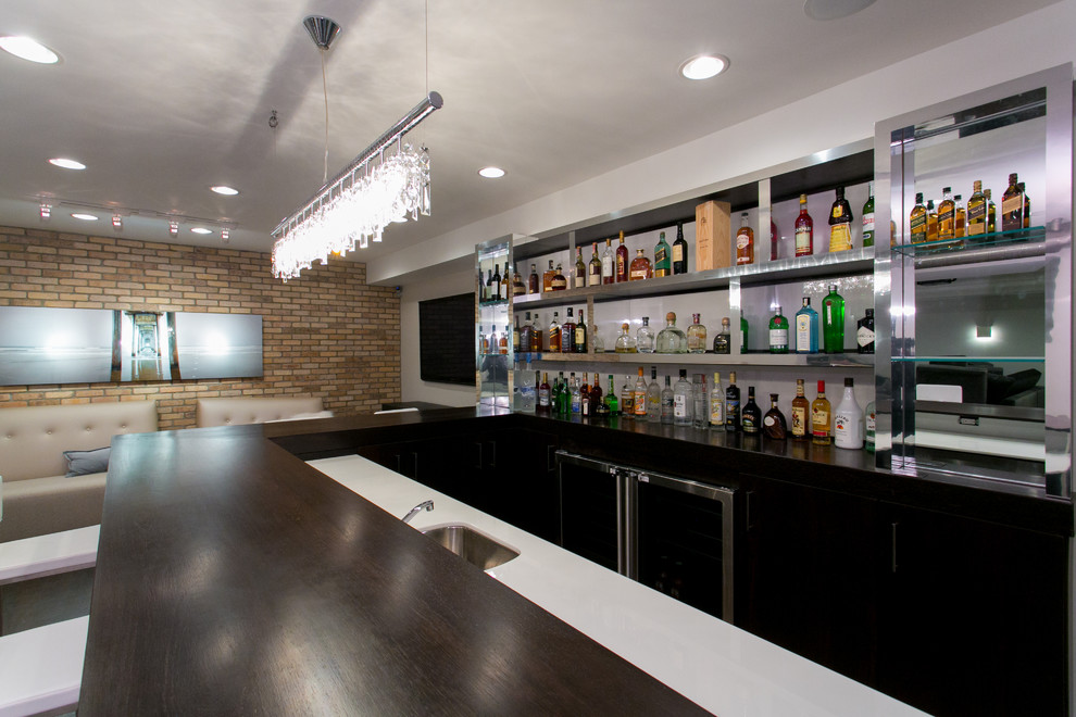 Example of a large trendy u-shaped dark wood floor seated home bar design in New York with glass countertops, white backsplash and black cabinets
