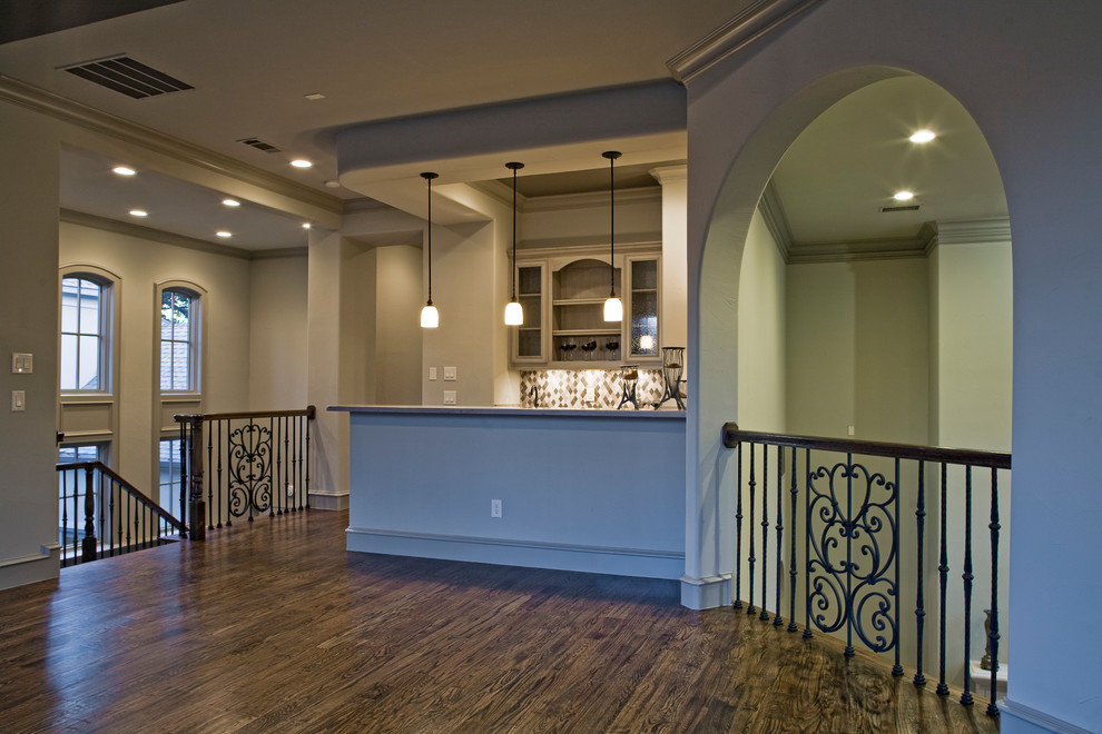 Inspiration for a mid-sized mediterranean u-shaped dark wood floor and brown floor seated home bar remodel in Dallas with an undermount sink, glass-front cabinets, gray cabinets, limestone countertops, beige backsplash, limestone backsplash and brown countertops