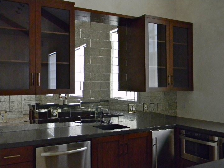 Cette image montre un bar de salon traditionnel de taille moyenne avec un évier posé, un placard à porte vitrée, des portes de placard marrons, un plan de travail en béton et une crédence miroir.