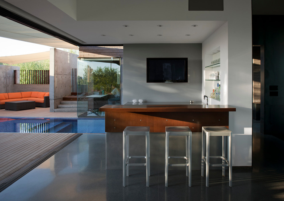 Imagen de bar en casa con barra de bar de galera moderno de tamaño medio con armarios abiertos, encimera de madera, suelo de cemento, suelo gris y encimeras marrones