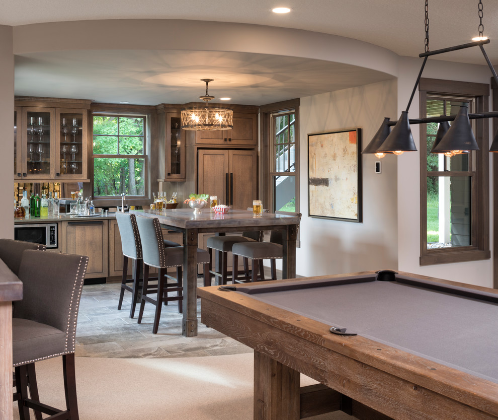 Inspiration for a large transitional u-shaped porcelain tile and gray floor wet bar remodel in Minneapolis with a drop-in sink, recessed-panel cabinets, brown cabinets, quartzite countertops and mirror backsplash