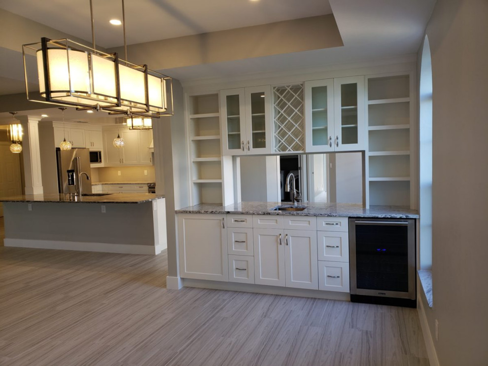 Mid-sized transitional single-wall vinyl floor and gray floor wet bar photo in Miami with an undermount sink, recessed-panel cabinets, white cabinets, granite countertops and multicolored countertops
