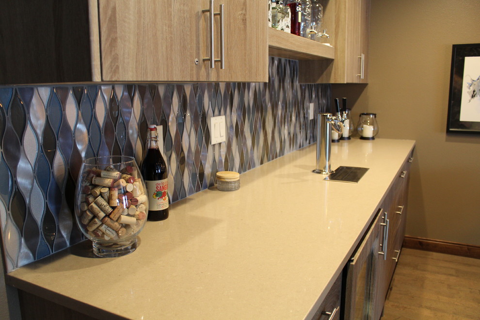 Example of a mid-sized transitional single-wall medium tone wood floor wet bar design in Other with flat-panel cabinets, medium tone wood cabinets, blue backsplash and glass tile backsplash
